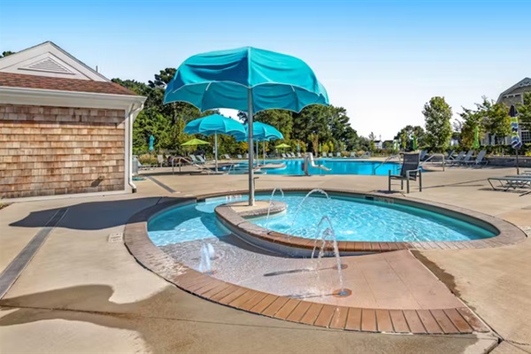Shallow kids’ pool with playful fountains and umbrella shade—perfect for little ones to splash safely.