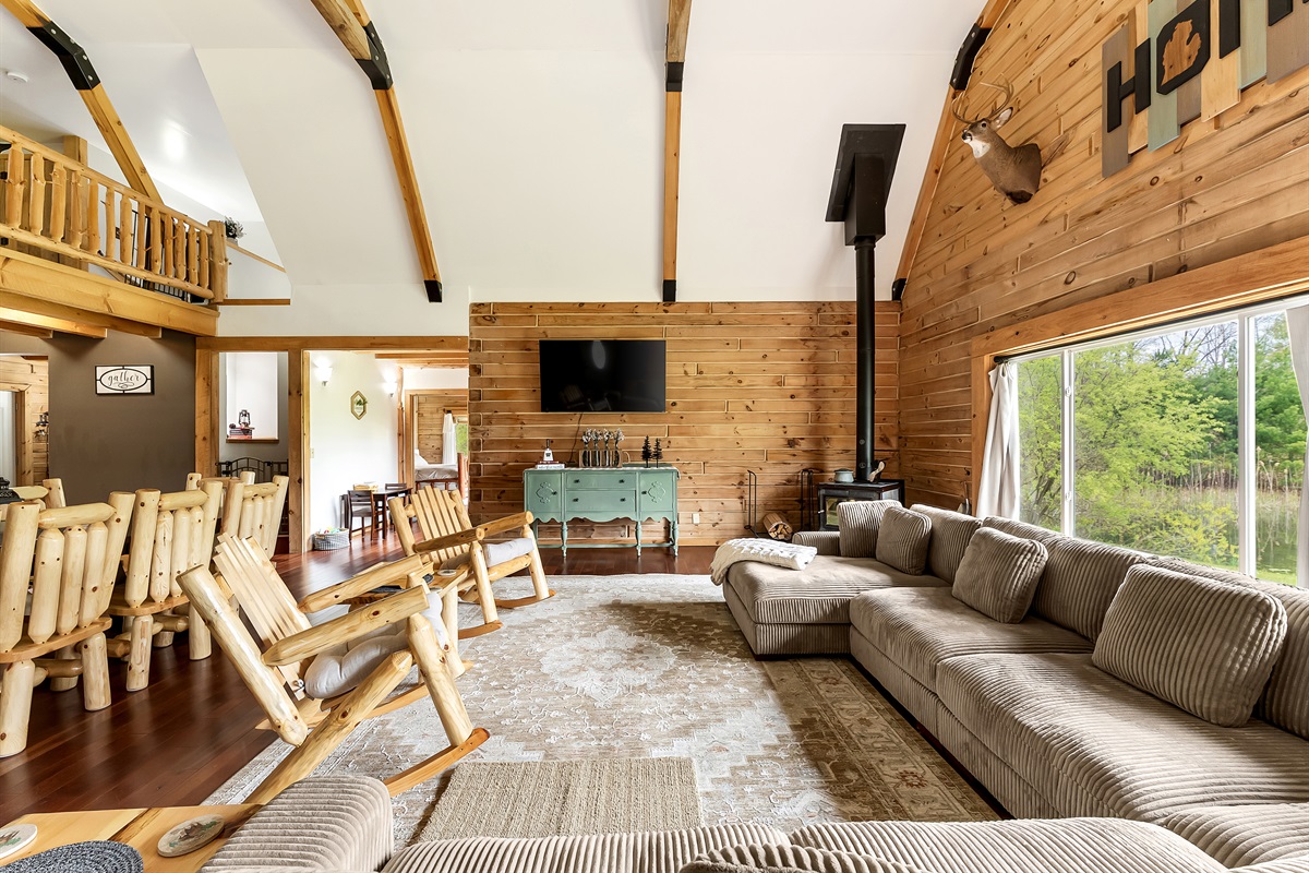 Living room view of TV and wood stove with large windows bringing in lots of natural light.