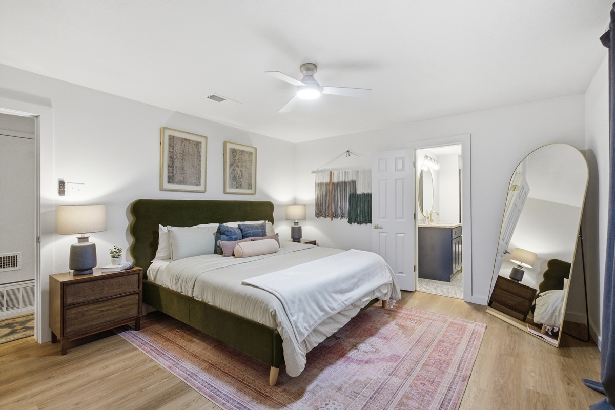 King Bed with full-length mirror, warm lighting, and room-darkening shades. Clothing storage and hardwood floors throughout. One of two King suites in this group rental.