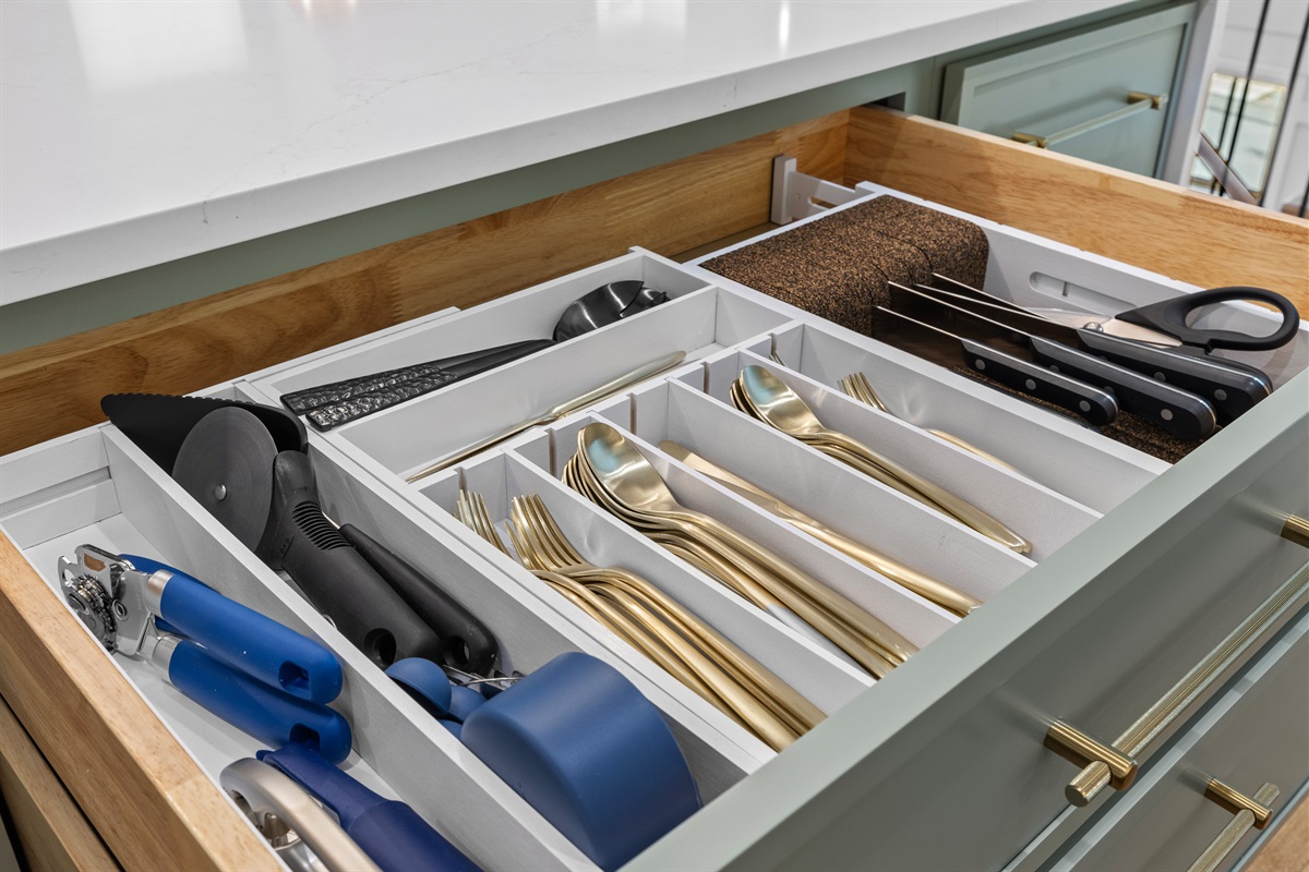 Fully stocked drawers with gold flatware and kitchen tools, ready for cooking in style.