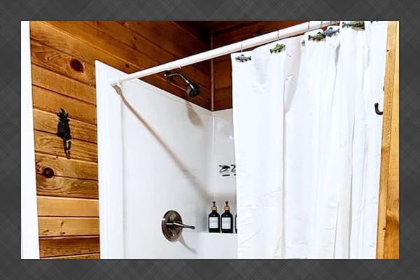 Enjoy a refreshing rinse in the clean, step-in shower featuring rustic wood surroundings, a sturdy bench seat, and complimentary shampoo, conditioner, and body wash, everything you need for a cozy, convenient stay.