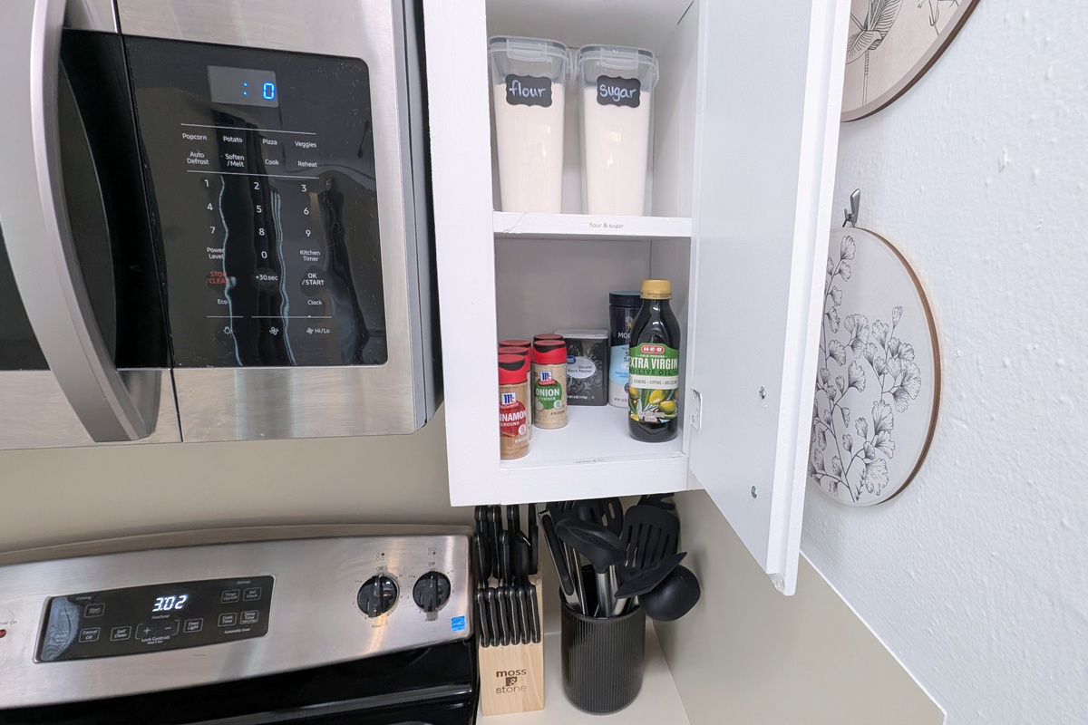 You’ll find essential staples like spices, oil, sugar, and flour stored by the stove, along with knives and cooking utensils for easy access.
