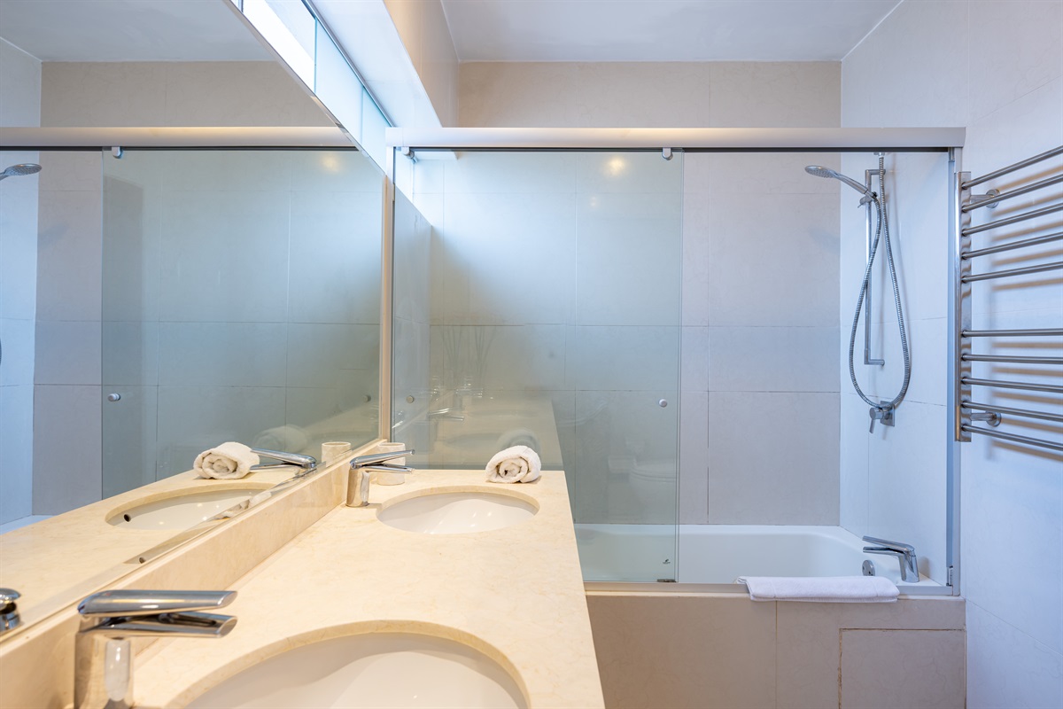 En-suite master bathroom with shower, towels, and complimentary toiletries  /  Baño en suite del dormitorio principal con ducha, toallas y artículos de tocador de cortesía