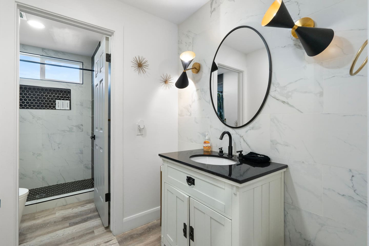 Stylish guest bathroom with marble tile, modern sconces, walk-in shower, and designer finishes.