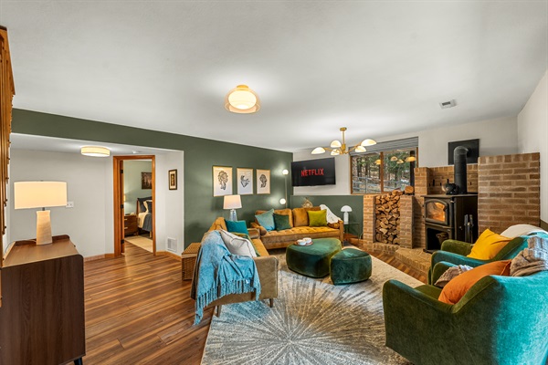 🛋️🔥 Comfy, colorful living room with plenty of seating, a crackling wood stove, and warm cabin vibes—perfect for movie nights, board games, and cozy conversations 🌲✨