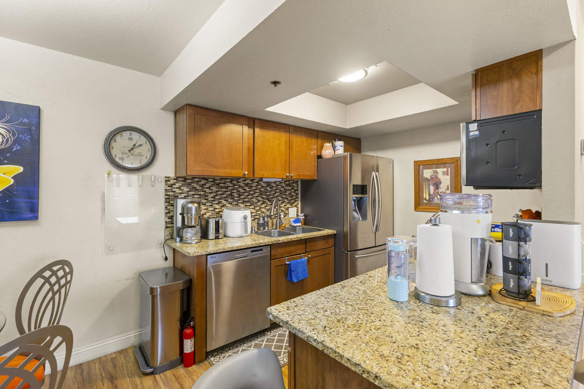 Kitchen counter with granite workspace, coffee setup, full appliances, and dining seating just beside it.
