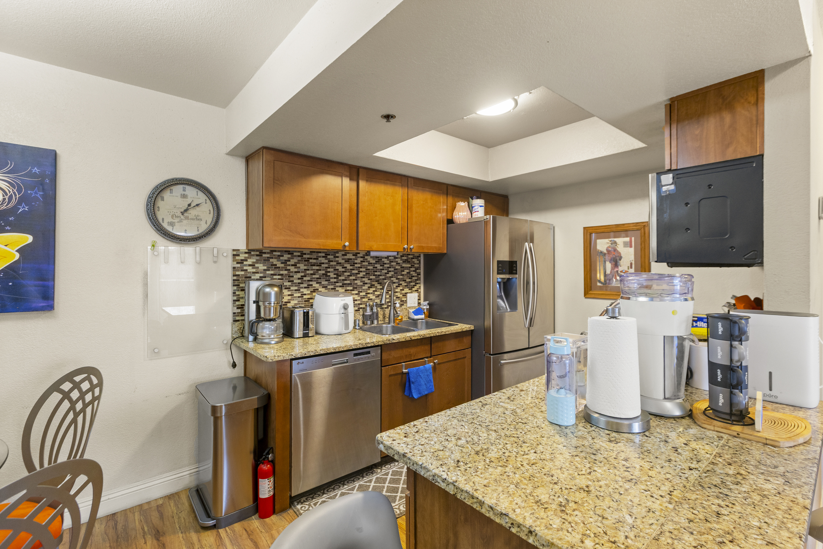Kitchen counter with granite workspace, coffee setup, full appliances, and dining seating just beside it.
