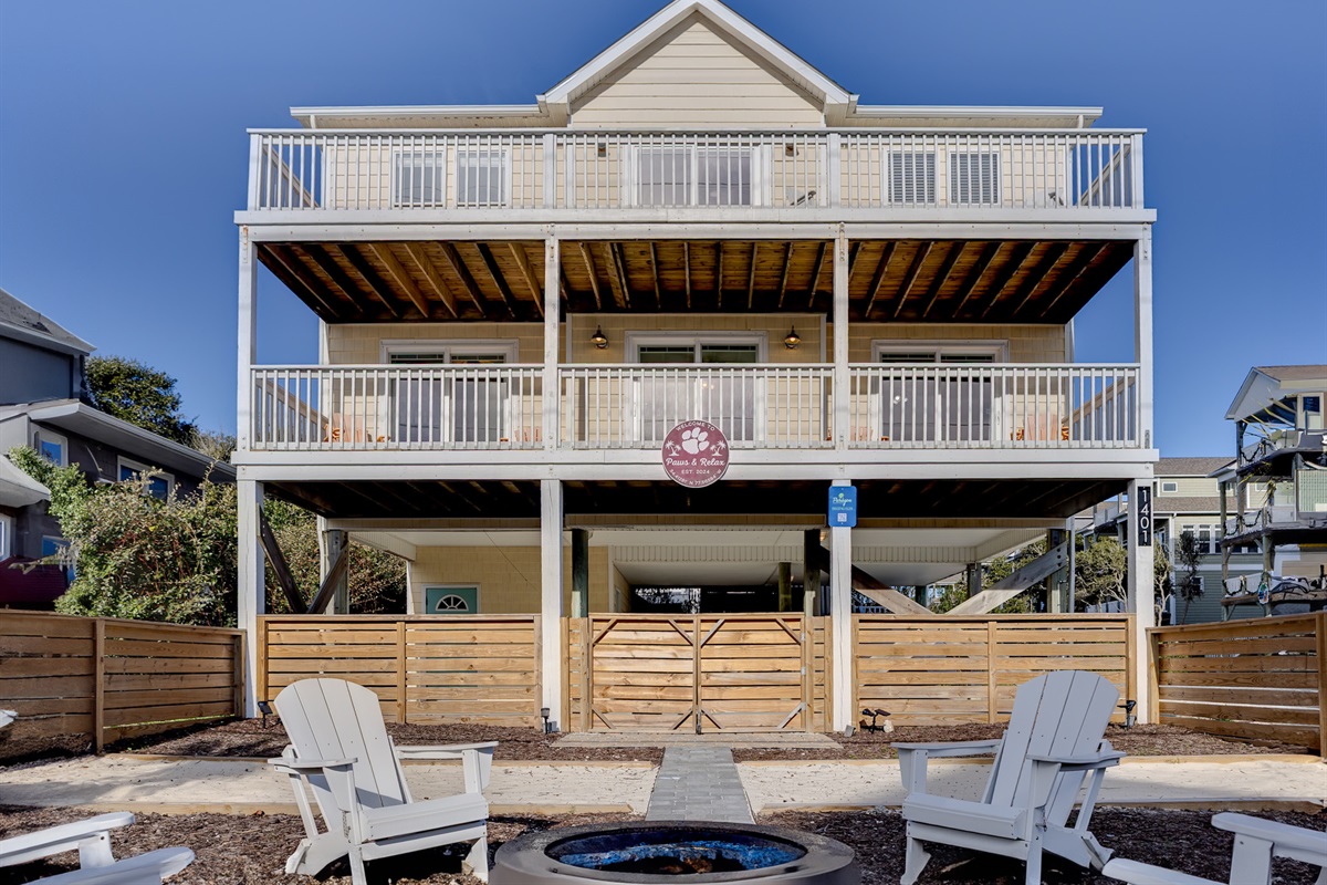 A beautifully designed beach home featuring expansive multi-level decks, a private fenced yard with fire pit seating, and plenty of outdoor space to unwind