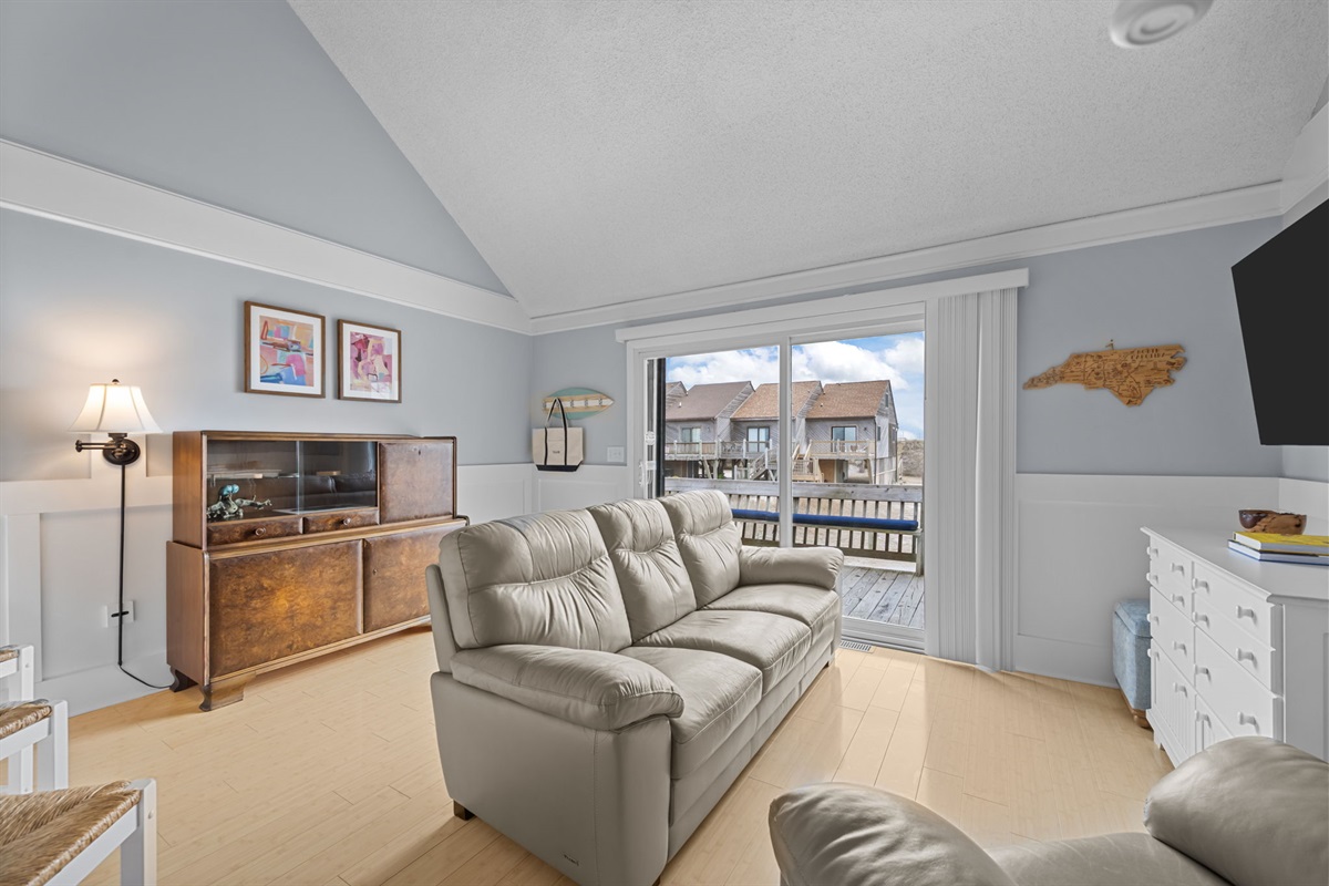 Natural light pours in through the sliding doors, connecting the living room to the deck and ocean breeze outside