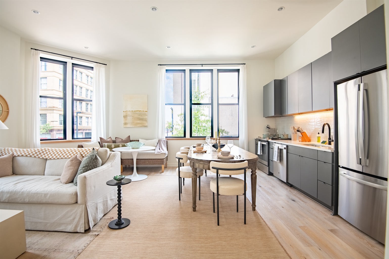 Bright open-concept living and dining space with large windows and modern finishes