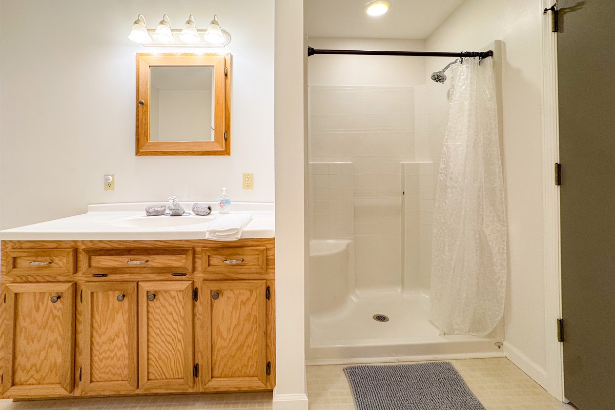 The ensuite bathroom features a tub/shower combination, toilet, vanity, grab bars, and a separate stall shower with low clearance! A rare treat!