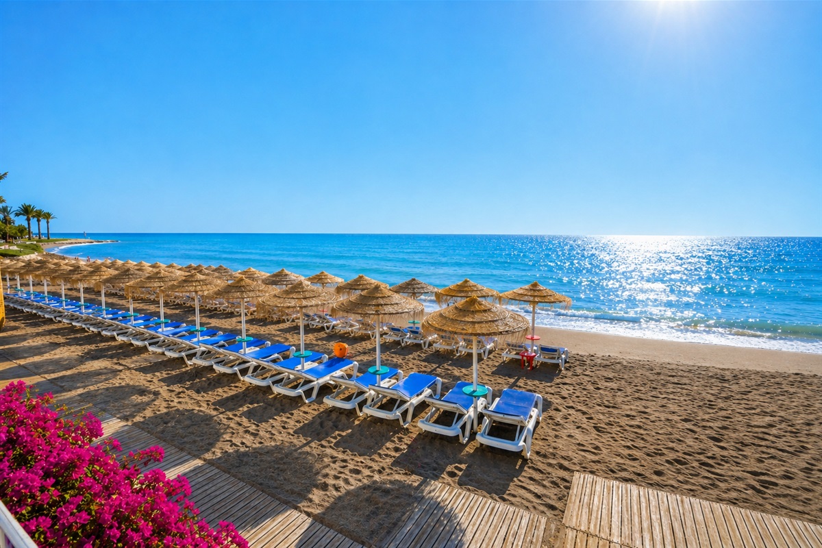 Bil Bil Beach, Benalmádena – A beautiful stretch of golden sand along the Costa del Sol, featuring crystal-clear waters, sun loungers under traditional thatched umbrellas, and a peaceful Mediterranean atmosphere.