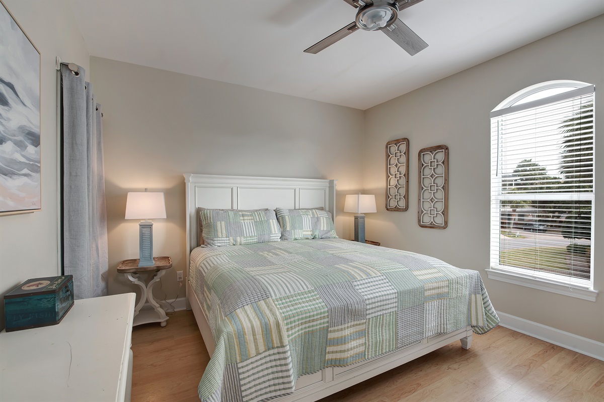 King bedroom with coastal bedding and natural light
