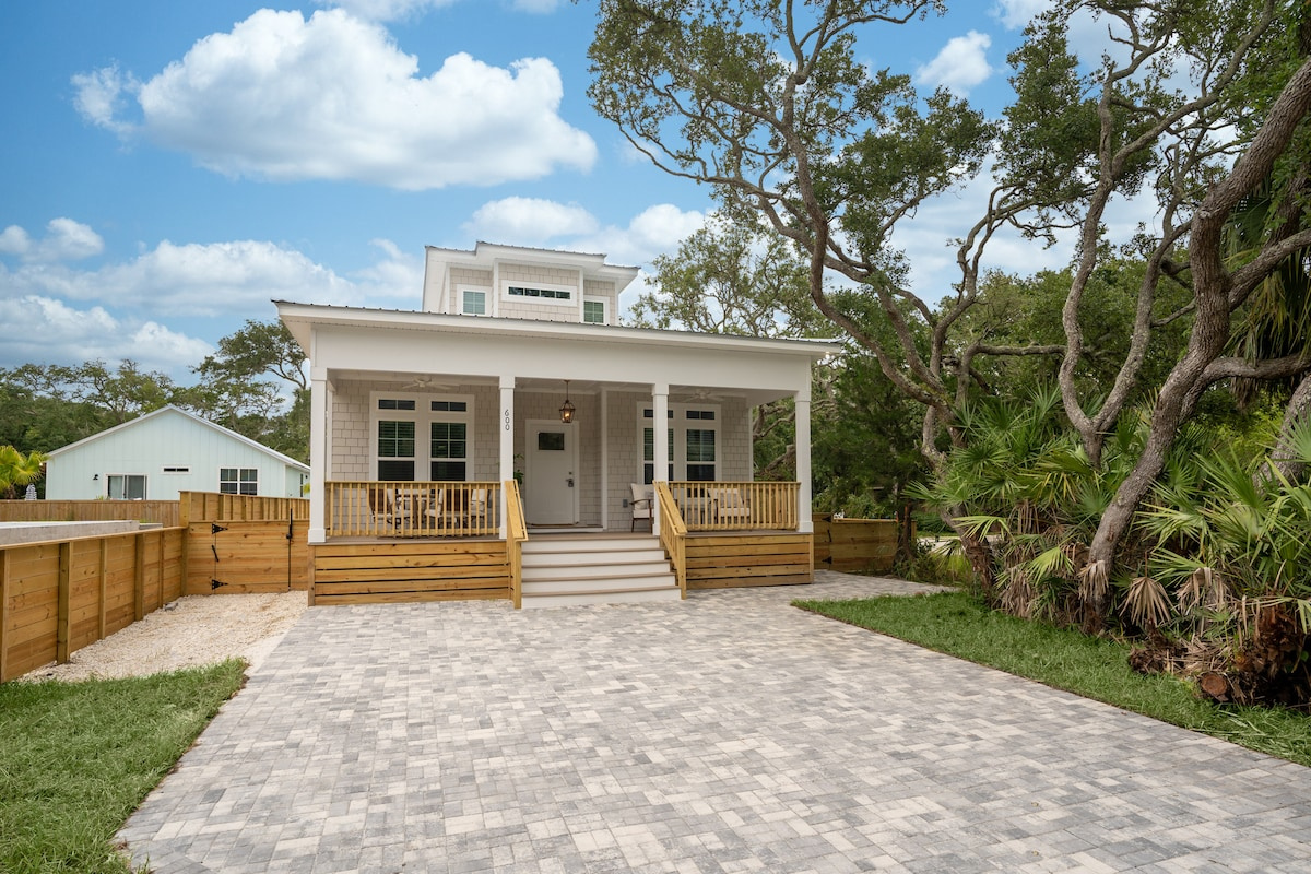 Pull onto the paver drive under the live oaks and you have arrived. Cedar shingles, a wide covered porch, and a quiet Vilano Beach street where the loudest sound most afternoons is somebody's screen door closing.