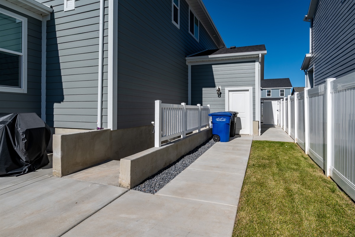 Private side walkway offering easy access and convenient trash area.