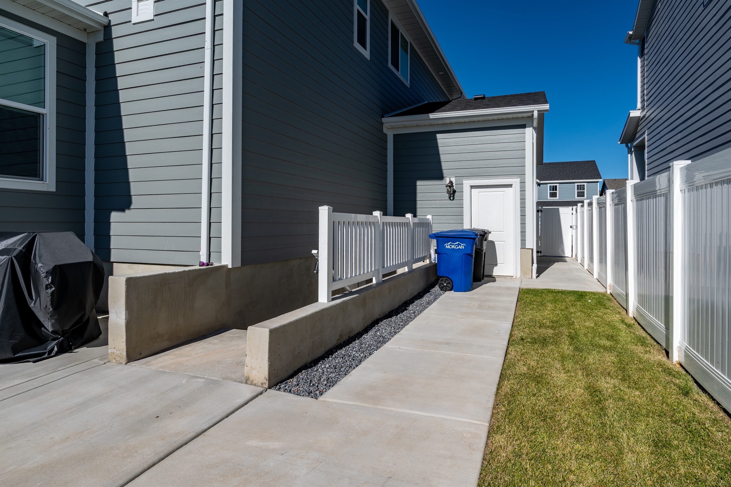 Private side walkway offering easy access and convenient trash area.