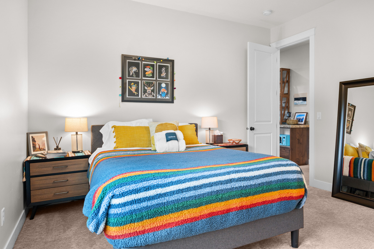 Spacious bedroom featuring plush bedding, bedside lighting, and direct access to the adjoining bathroom.