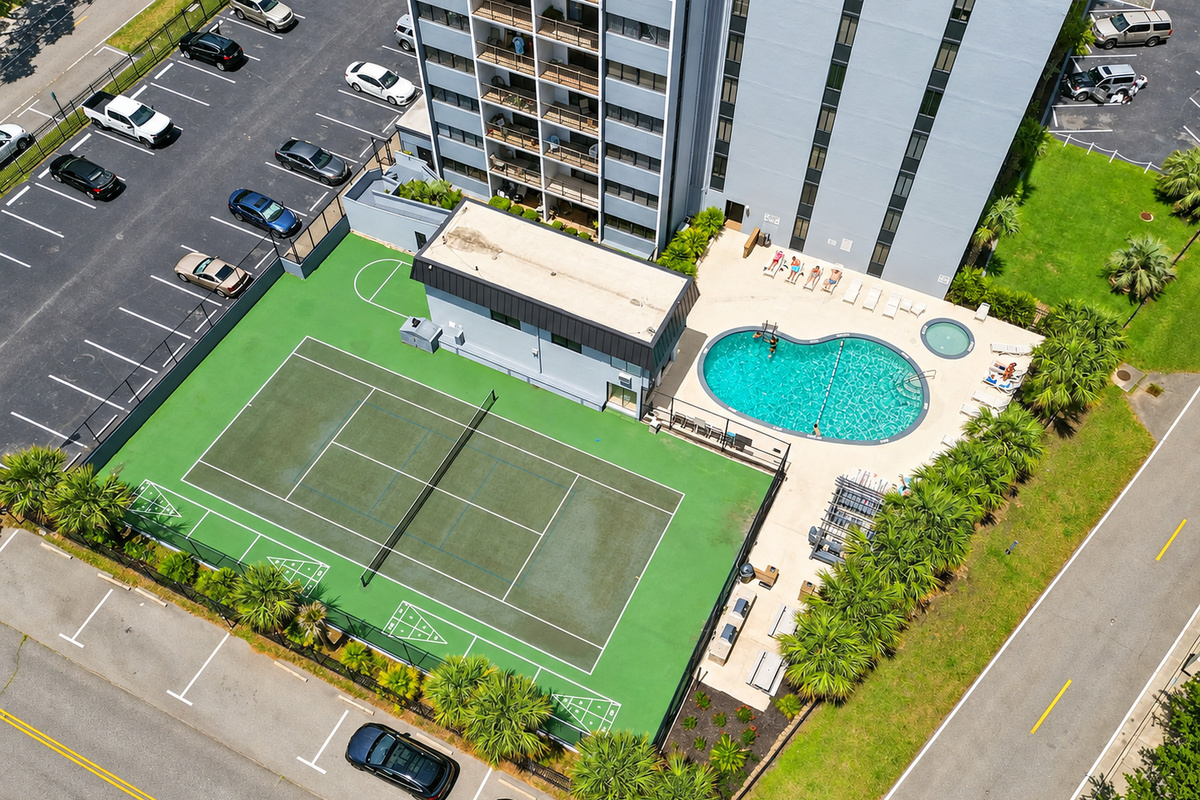 Aerial view of Holiday Towers with the shared pool, hot tub, tennis court, and guest parking all in one easy-access area.
