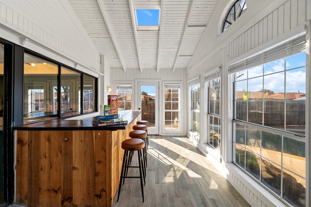 Bright and breezy sunroom with a sleek bar and four stylish barstools—perfect for cocktails or conversation.
