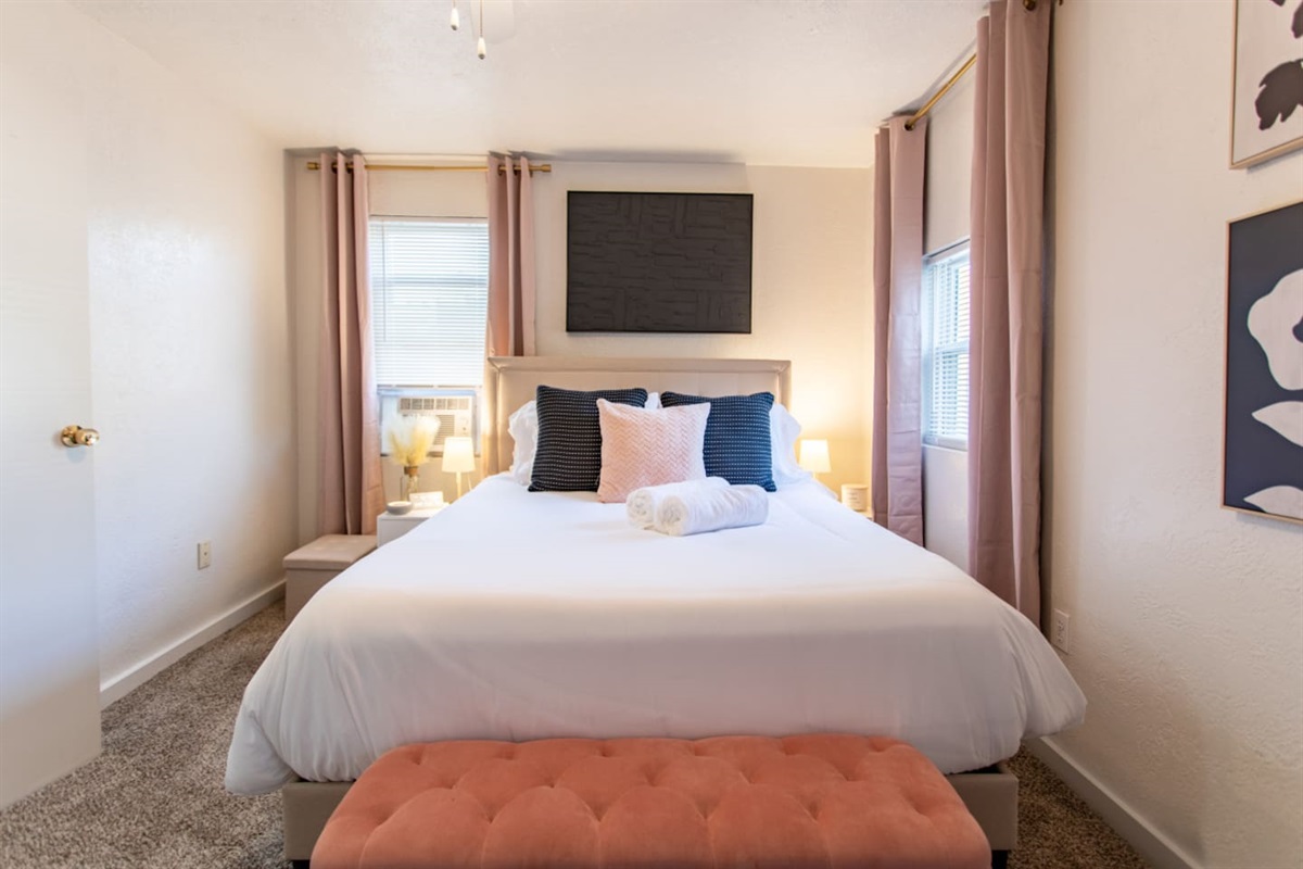 A cozy bedroom with windows on each side, allowing natural light to flood the room and create a bright, airy atmosphere for a peaceful retreat.