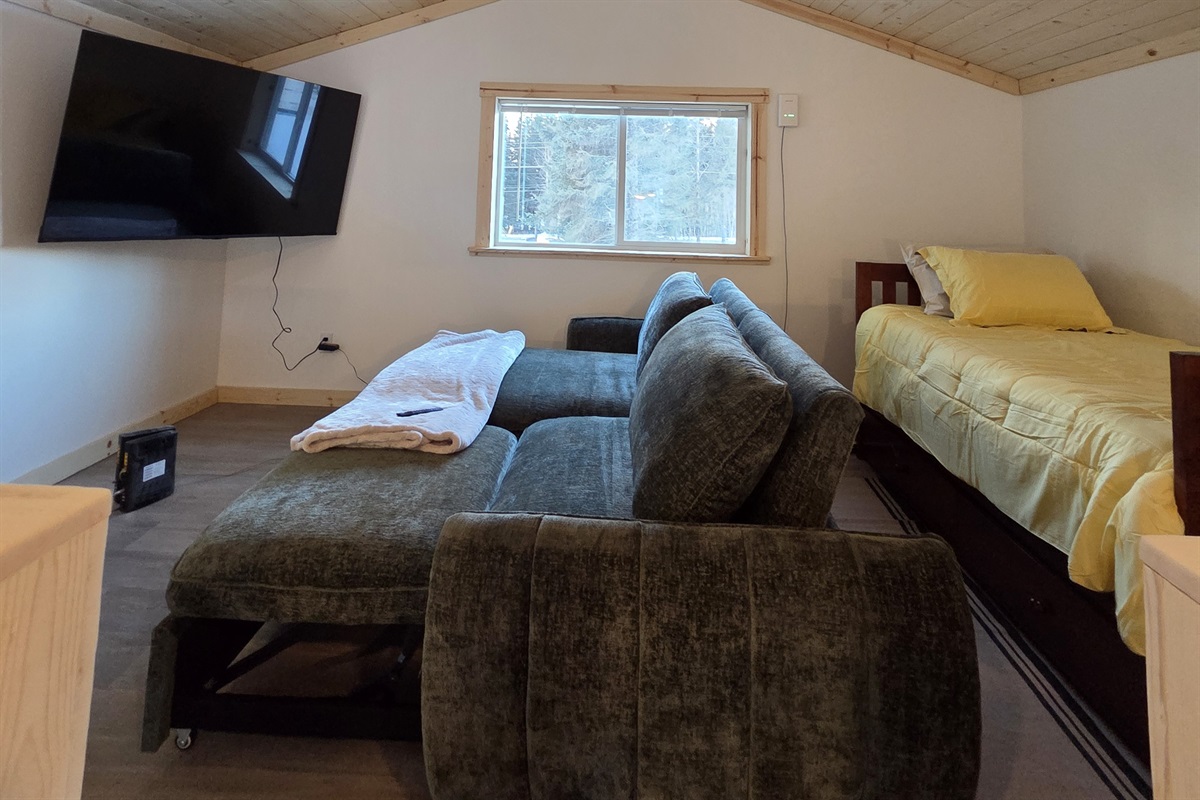 Loft area includes large swivel chair, sofa sleeper, and additional bed (twin bed with trundle bed)