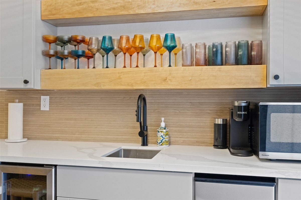 Downstairs kitchenette with sink, plastic drink-ware, microwave, mini fridge, ice maker and keurig.