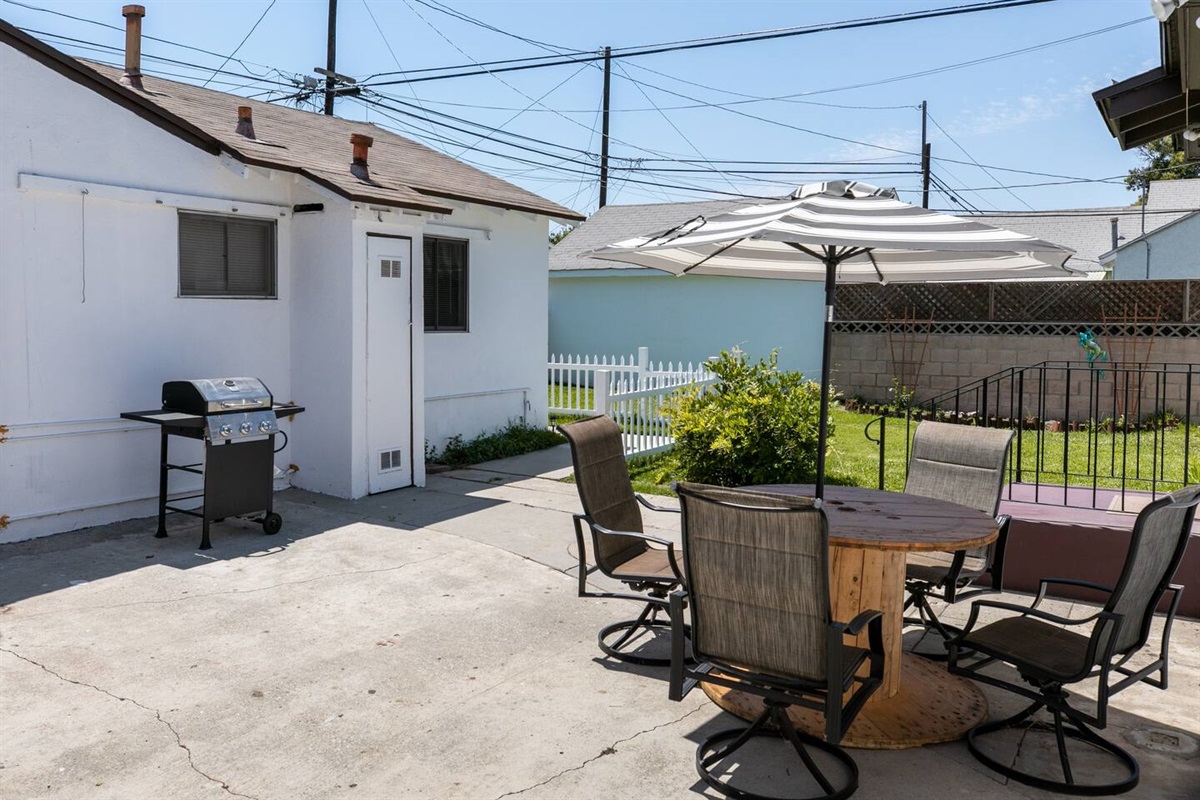 Back patio.  Relax with a cold beverage. Enjoy some California sunshine! Simple dining space, repurposed patio table shaded by umbrella.