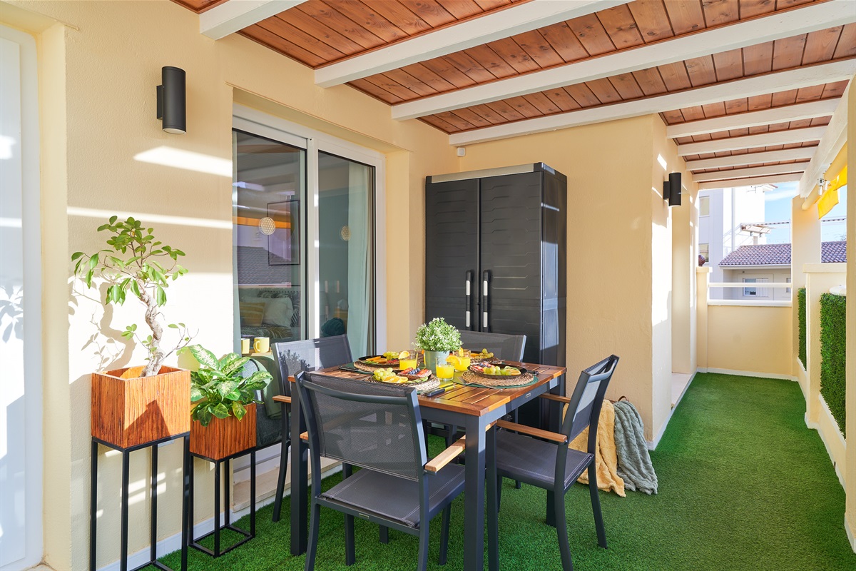 Private covered balcony with dining area, lush plants, and ambient lighting — ideal for a relaxed breakfast or a cozy evening meal.