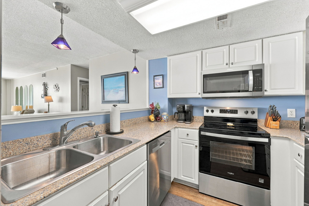 Fully equipped kitchen featuring white cabinetry, modern appliances, and a double-basin sink.