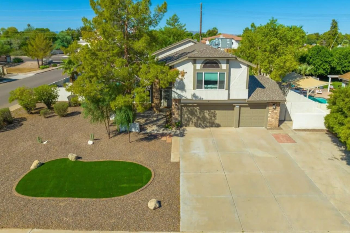 Two-story home with putting green, mature trees, spacious driveway, and resort-style backyard.
