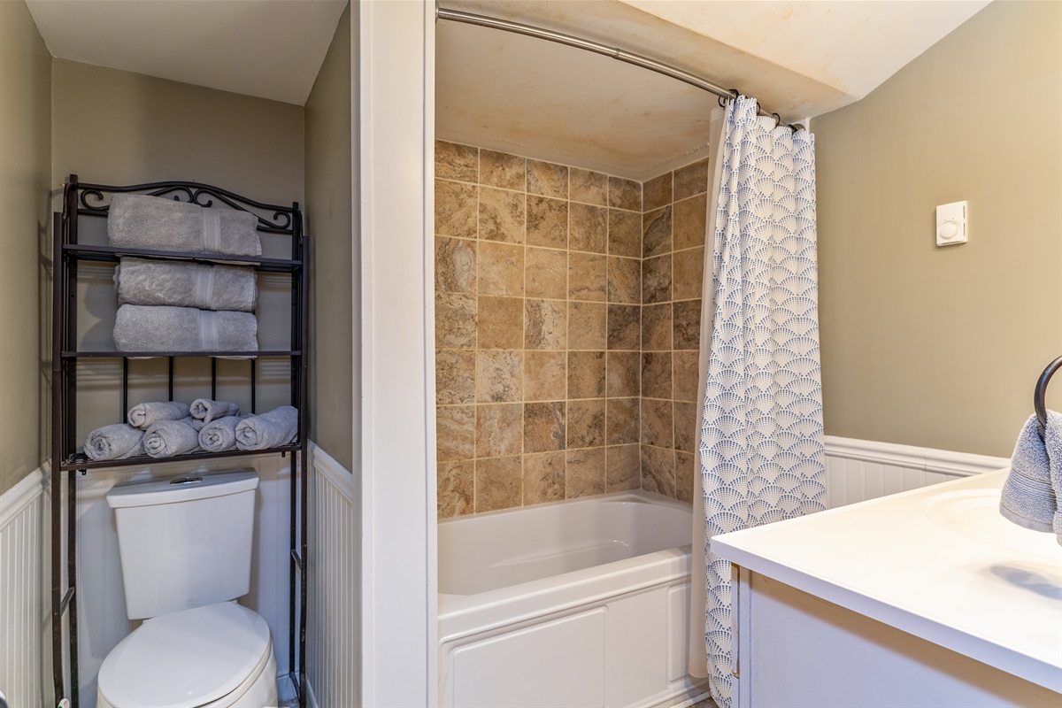 Clean and functional upstairs bathroom with a tiled shower/tub combo, stocked towels, and modern touches for guest comfort.