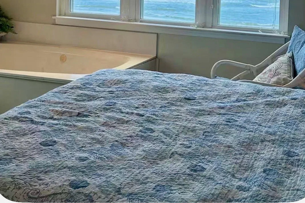 Primary bedroom: king bed with jetted tub beneath ocean-view windows