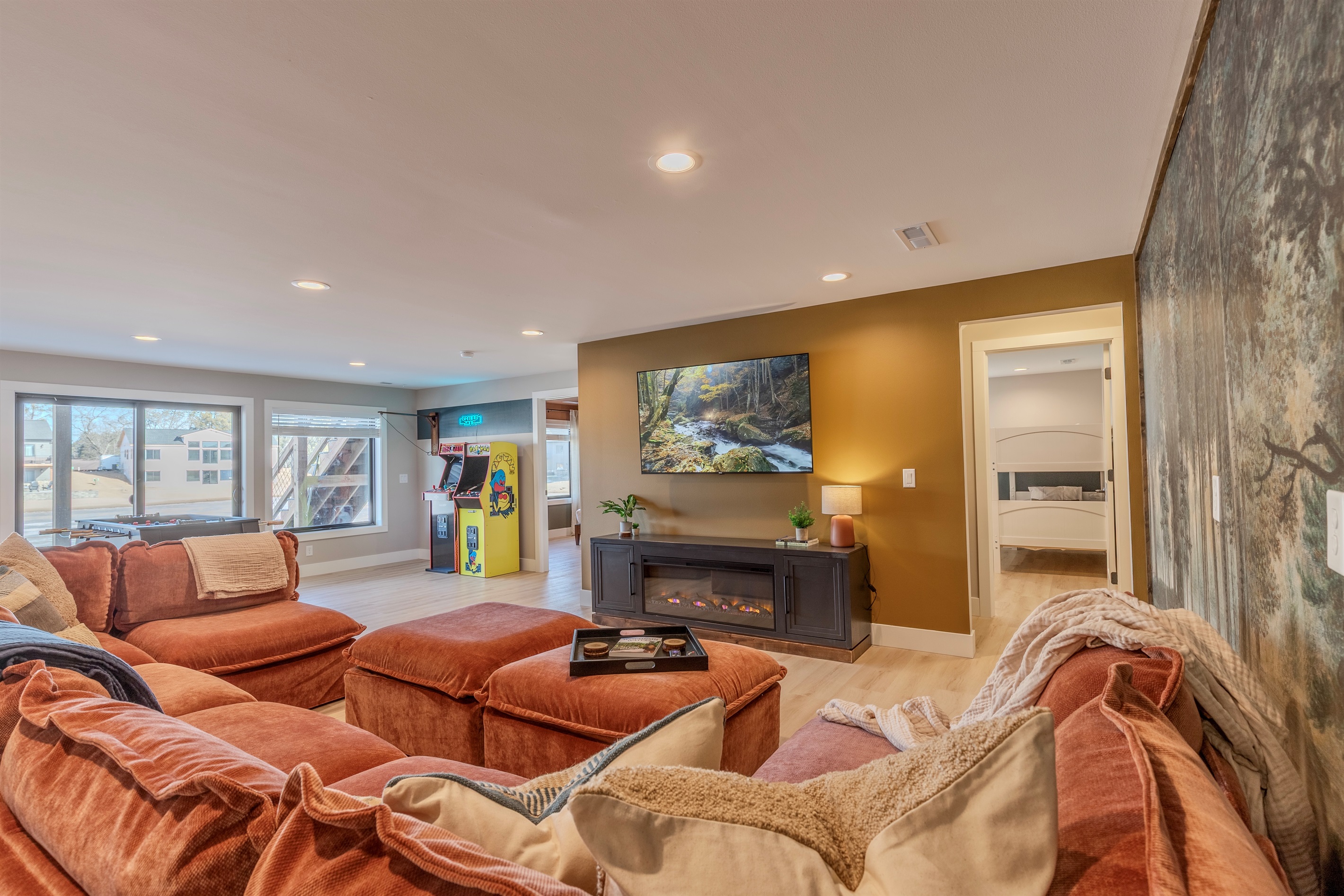 Downstairs open concept living area with large sectional sofa, electric fireplace and Roku TV.