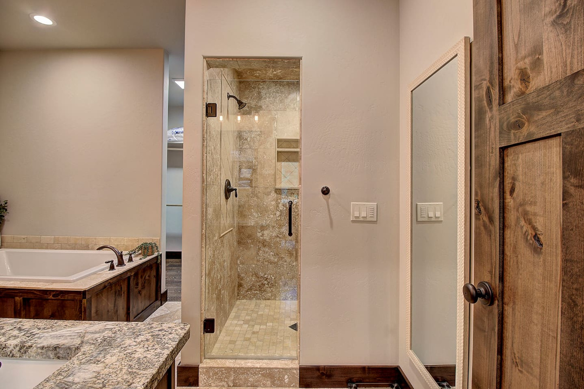 Walk-in tiled and stunning stone shower with a glass door for a spa-like experience.