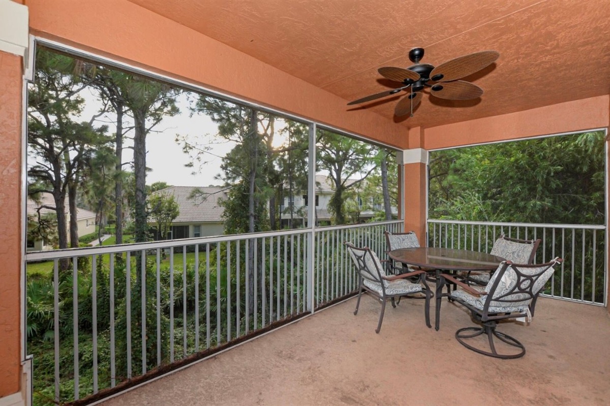Spacious screened balcony with seating and peaceful views of the surrounding greenery.