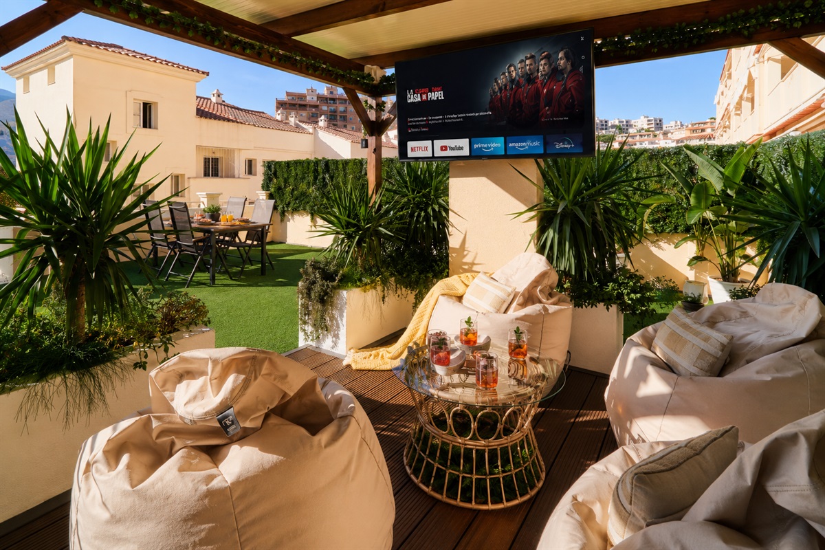Relax beneath the covered pergola with cozy seating, fireplace, and dining area. Perfect for long evenings, romantic dinners, or movie nights on the outdoor TV under soft ambient lights.
