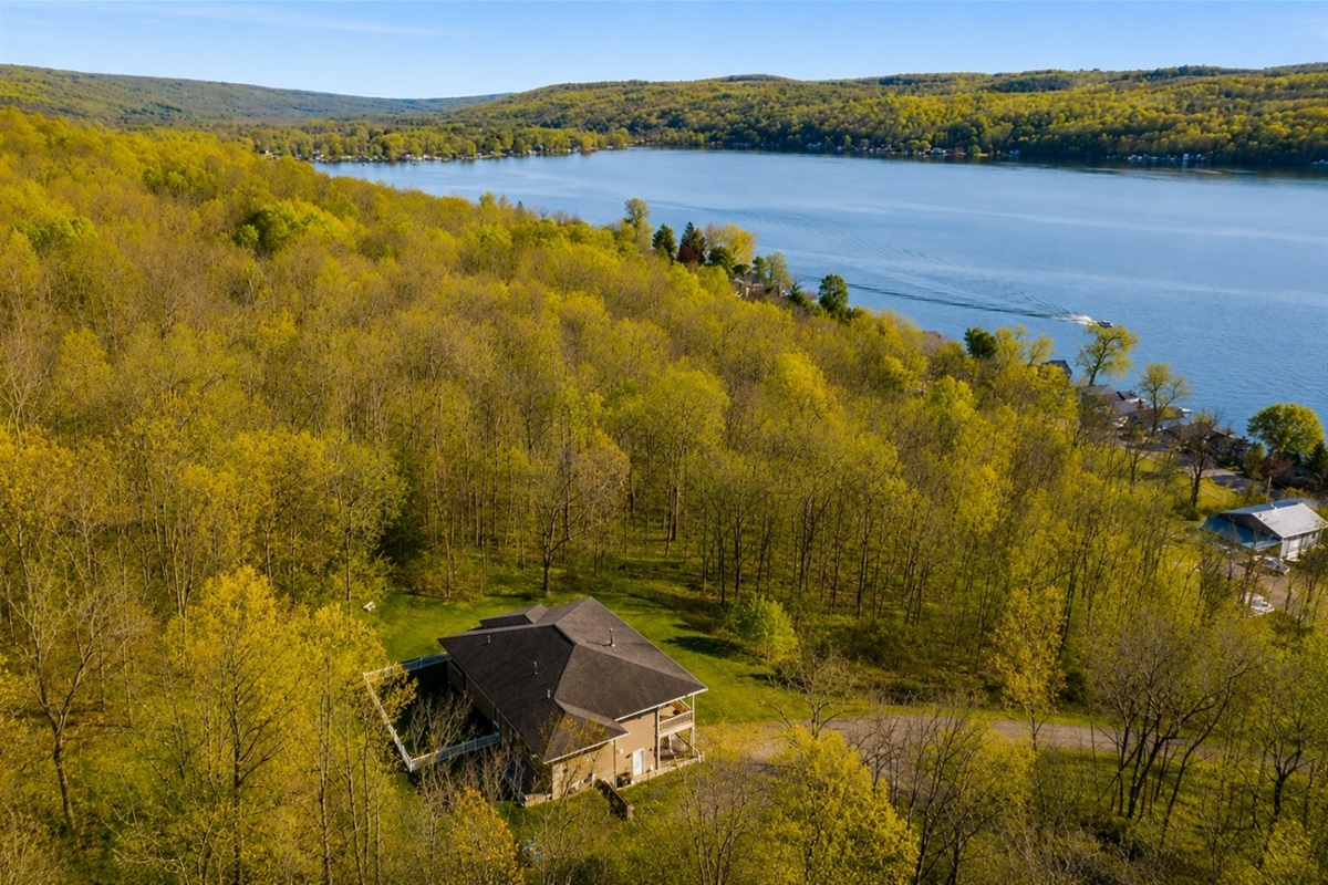 This aerial view showcases a stunning, modern home surrounded by lush greenery, featuring expansive outdoor living spaces and a serene setting, perfect for a luxurious retreat. 