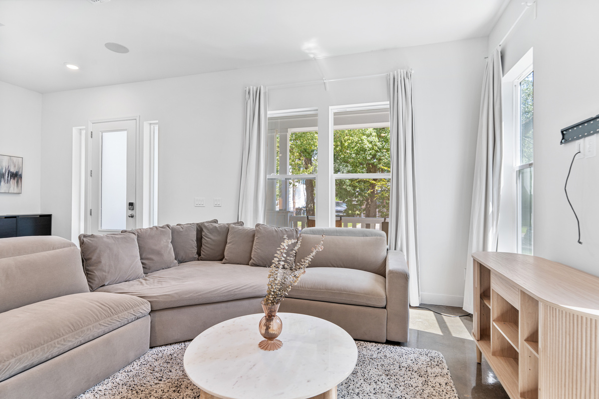 Come in and kick your shoes off. The sectional is deep enough for everyone and the front windows frame the oaks along the street. This is where your people end up each night, feet up, nobody going anywhere.