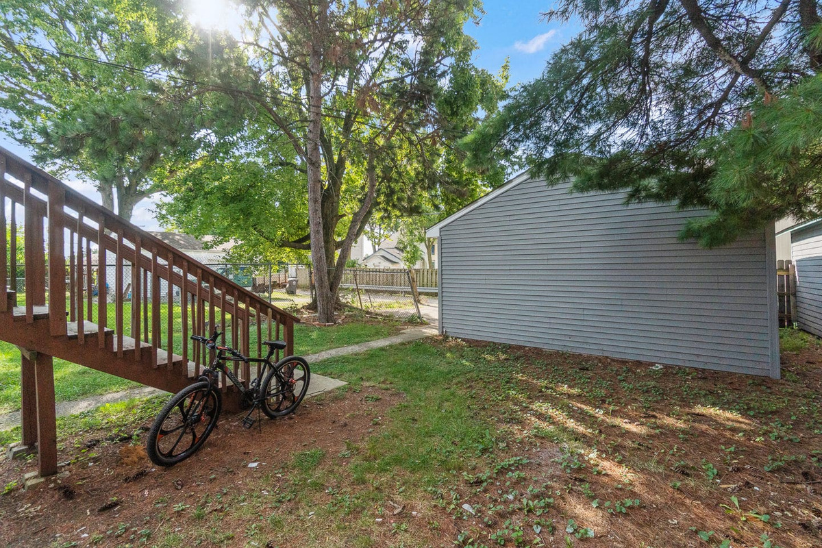 Backyard with mature trees and exterior staircase.