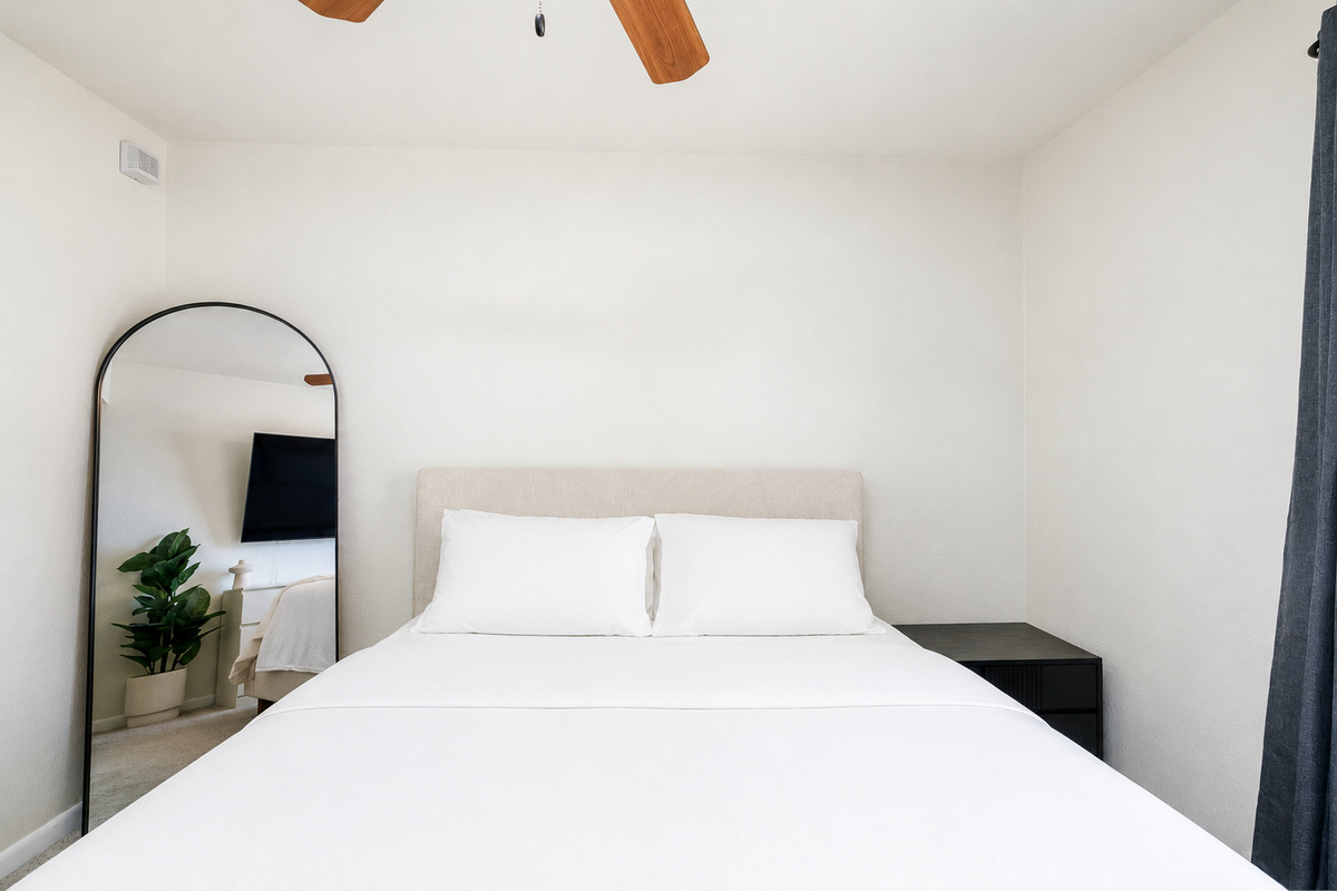 Bedroom with a queen bed, dresser, ceiling fan, and natural light for a comfortable rest.