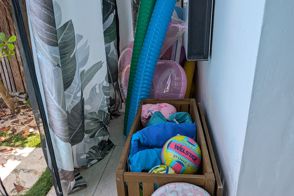 Wooden storage bin at Villa Coral packed with complimentary beach volleyballs, pool toys, life jackets, puddle jumpers, and colorful pool noodles in Dorado, Puerto Rico.