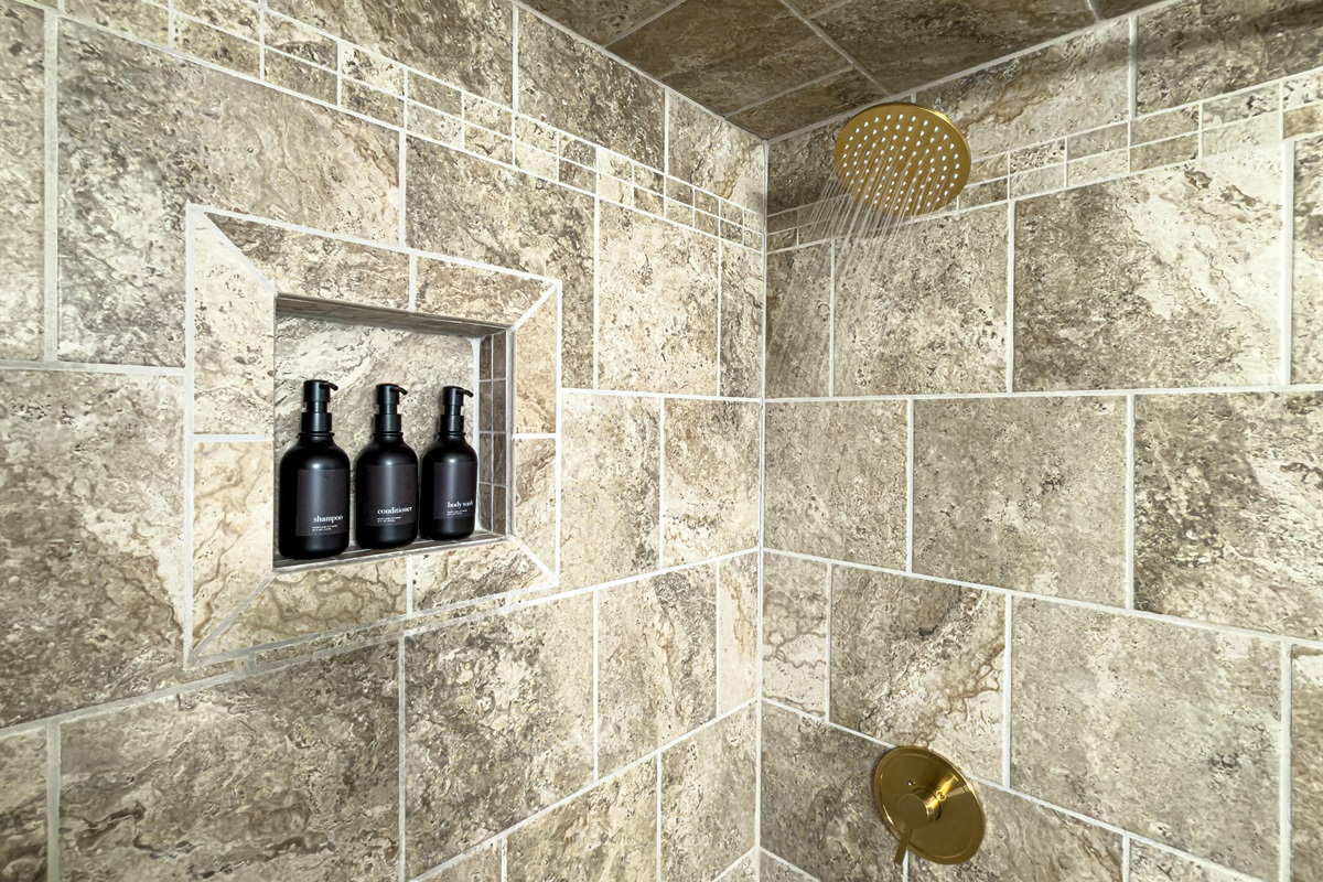 Tiled shower with shampoo, conditioner and body wash provide a relaxing rain shower after a fun day in the sand.