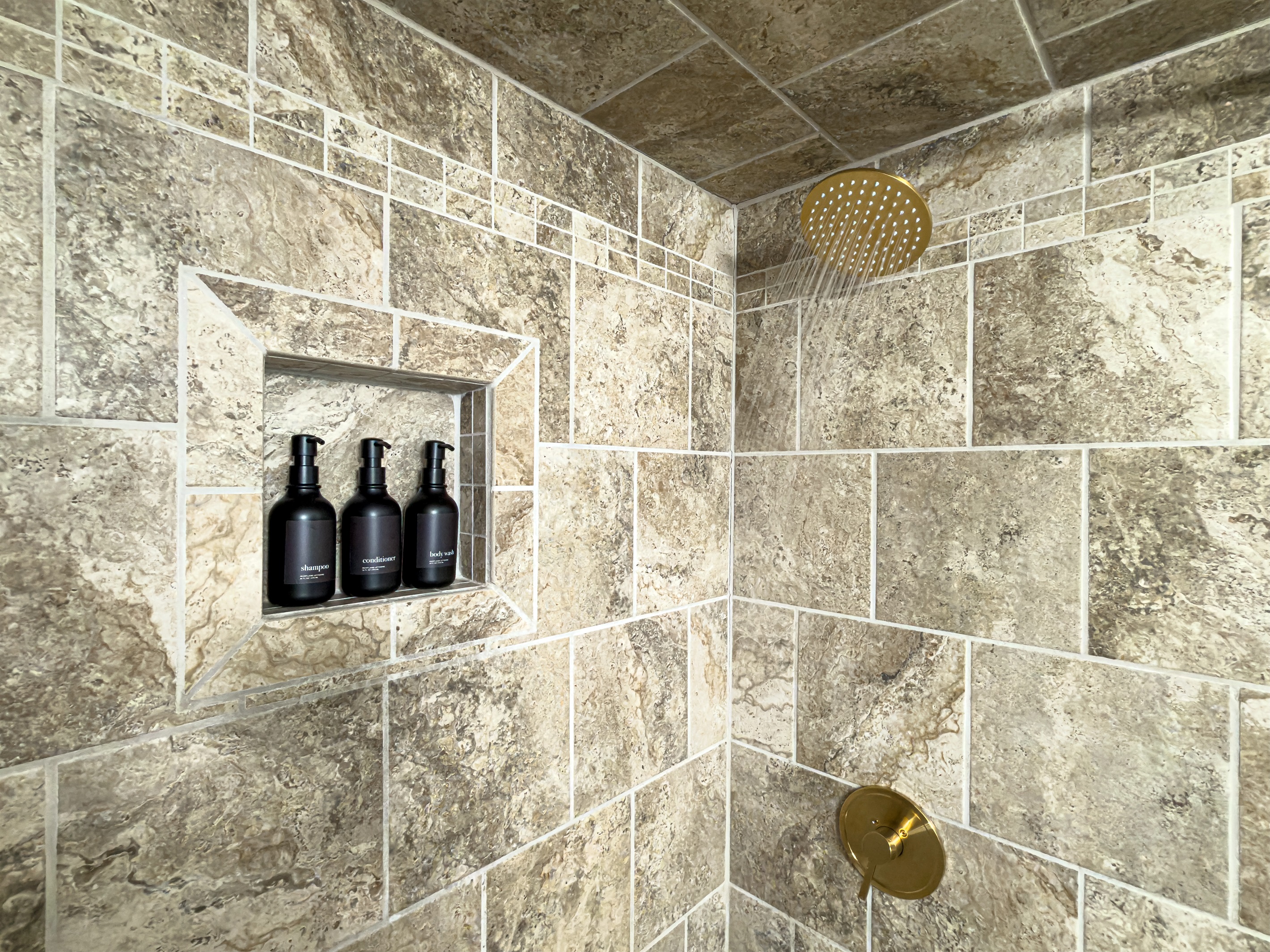 Tiled shower with shampoo, conditioner and body wash provide a relaxing rain shower after a fun day in the sand.