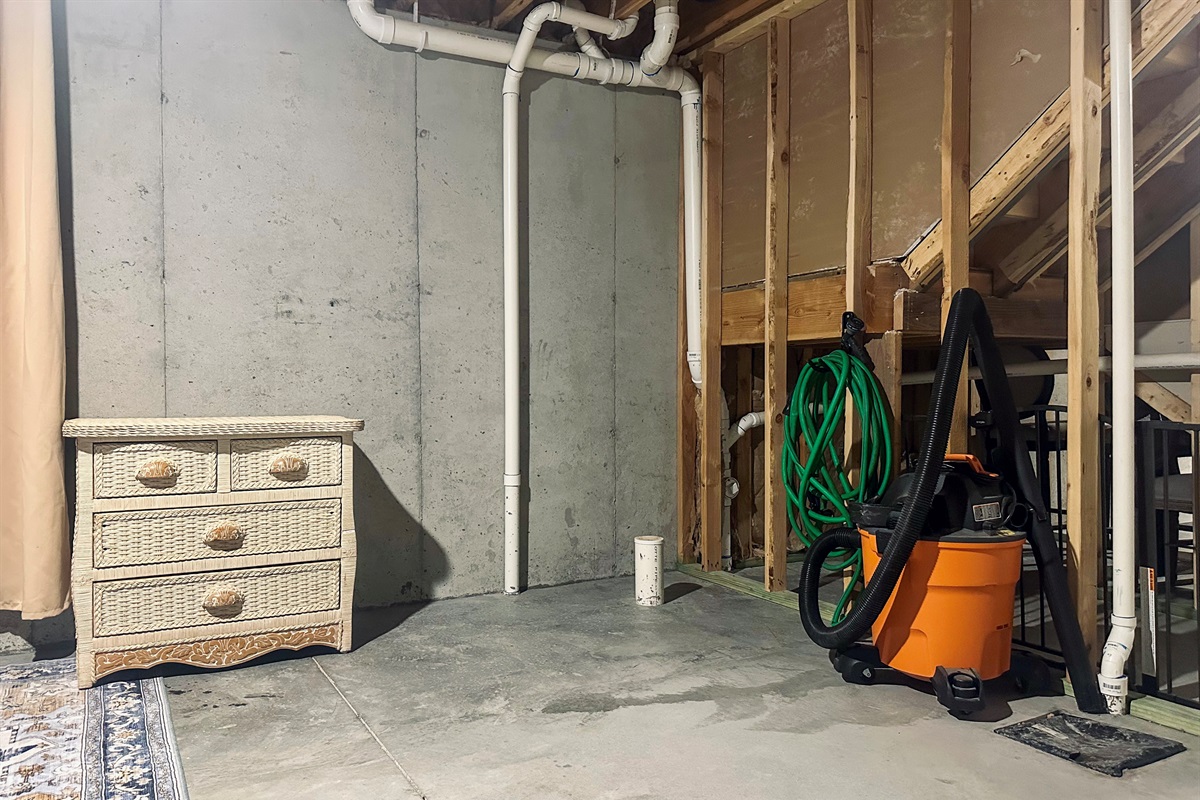 West basement storage area equipped with a shop vac and hose for guest convenience, with generous space for organized belongings.