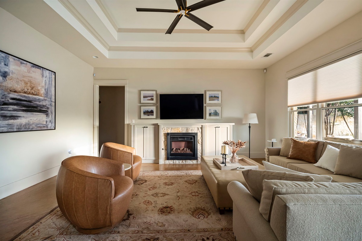 A spacious and inviting area featuring a large L-shaped sofa, two bucket chairs, and a TV for entertainment.
