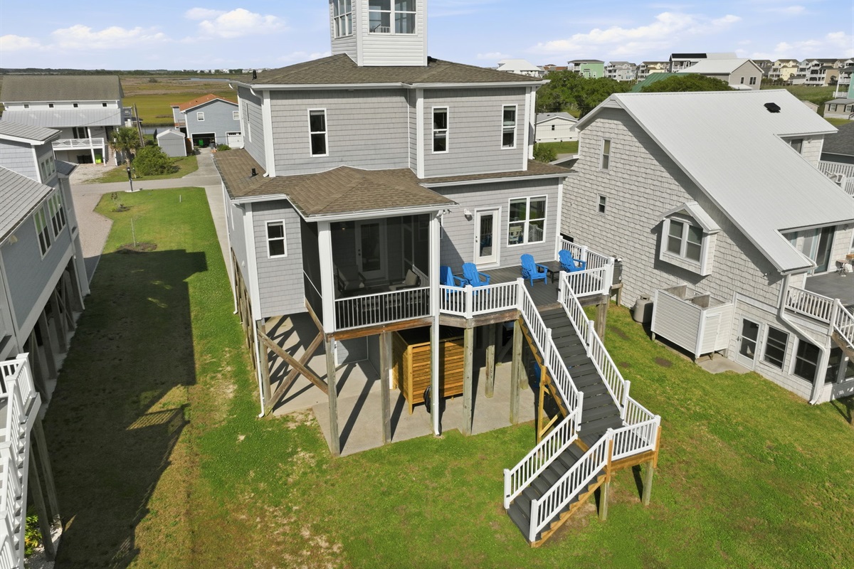 Rear aerial view highlighting the expansive outdoor living spaces, elevated design, and peaceful surroundings