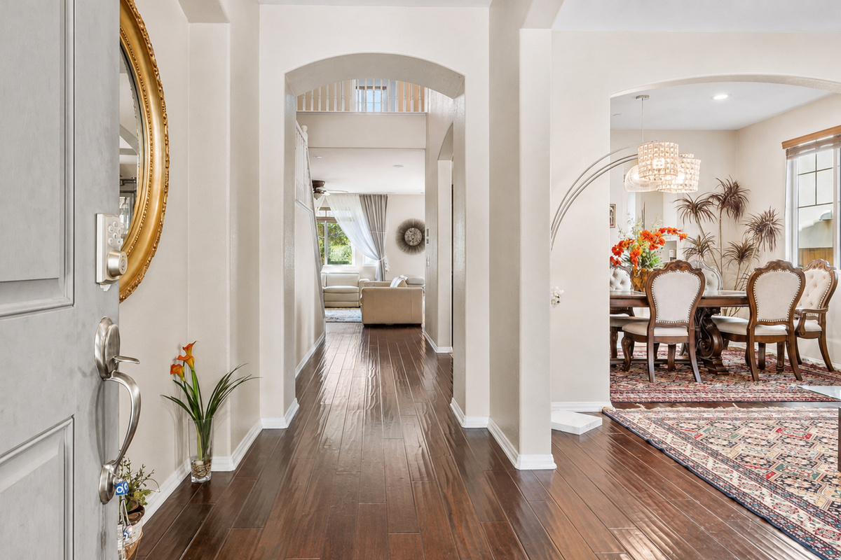 Entry hallway with polished wood floors, arched openings, and easy access to the dining and sitting rooms.