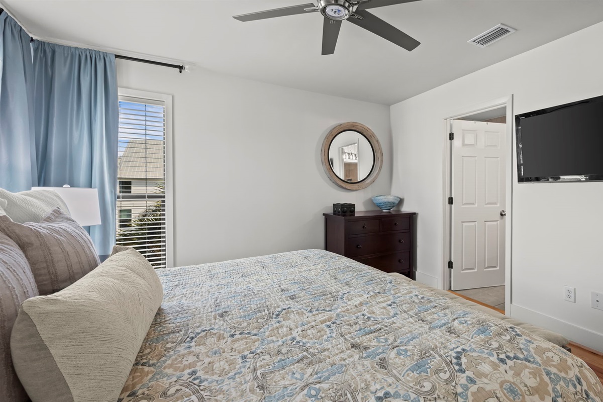Retreat to the master bedroom of our Cotton Bayou condo, featuring cozy bedding, updated coastal-inspired decor, and a private en suite for ultimate comfort. 