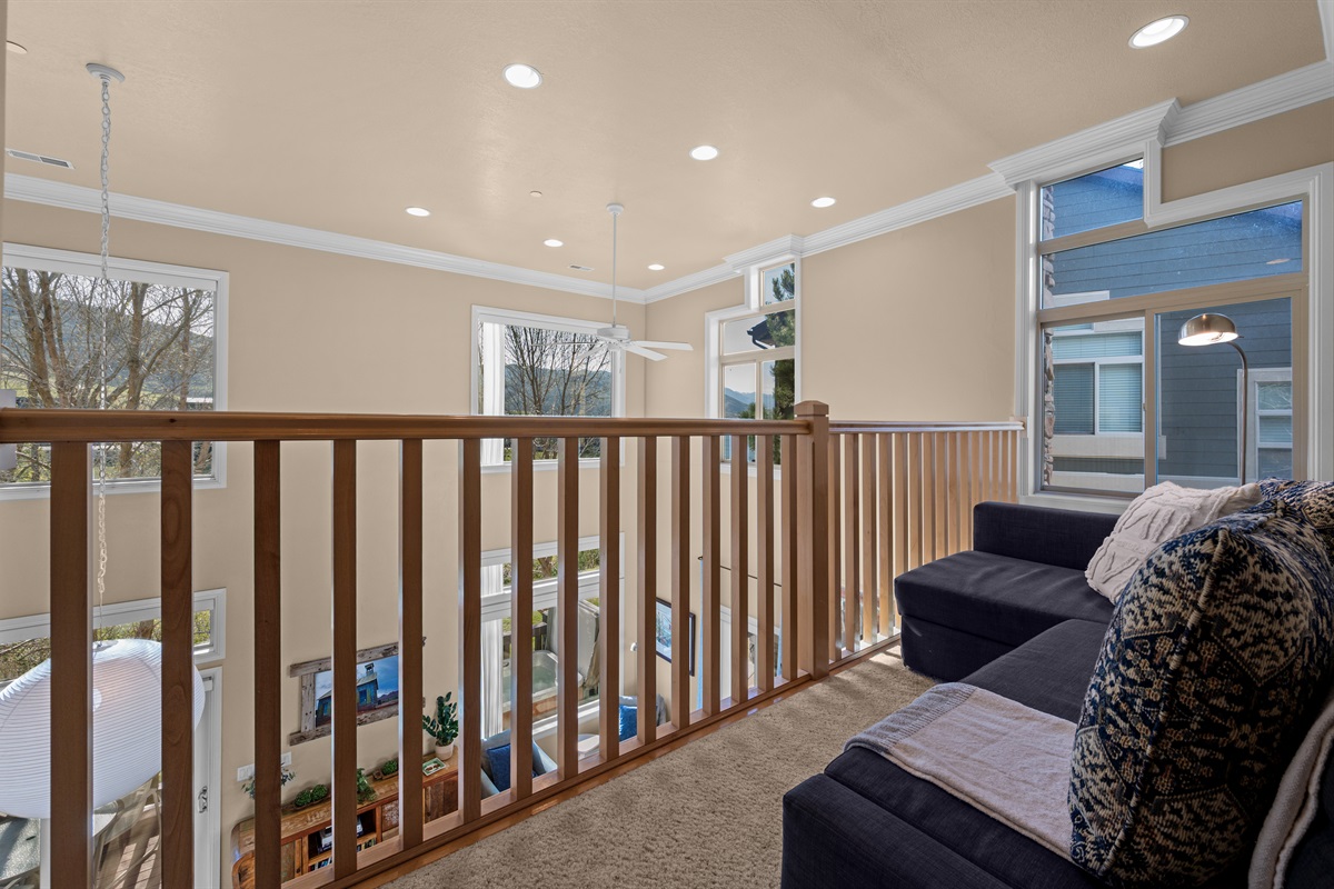 Open loft overlooking the great room below with soaring ceilings and abundant natural light.