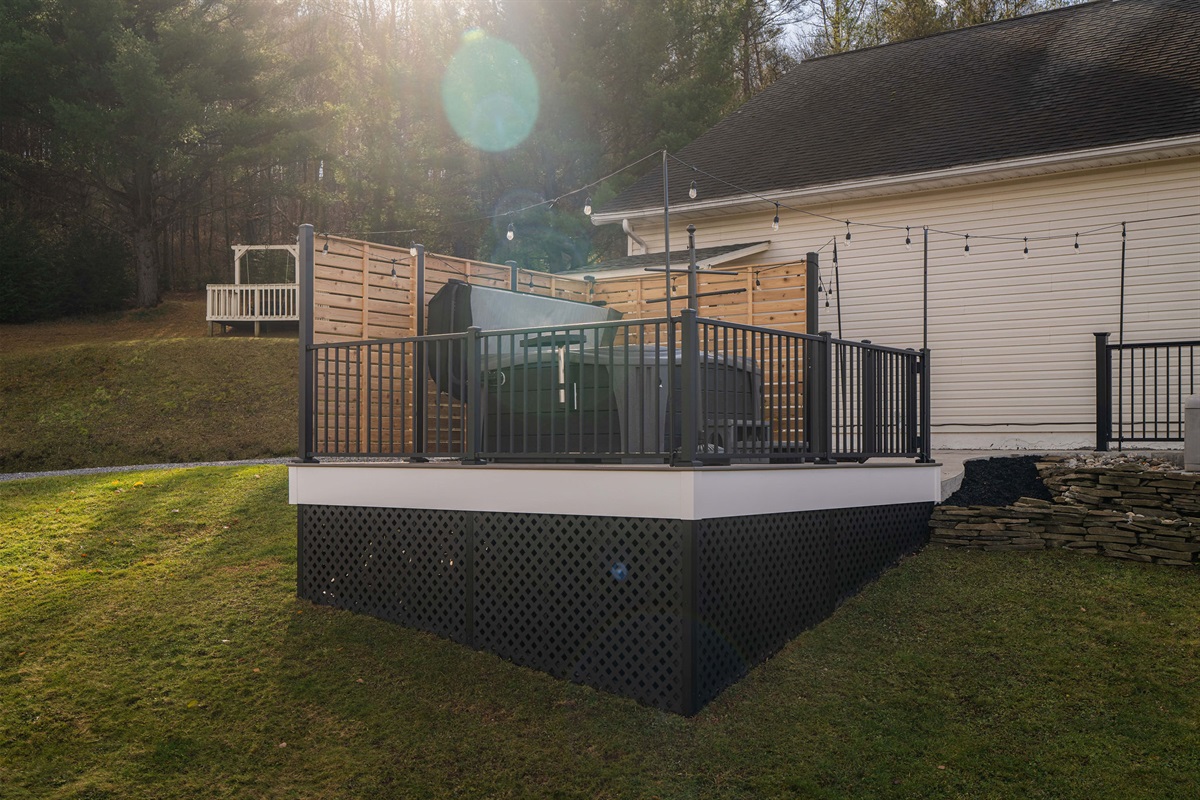 Private elevated hot tub deck with privacy screens and string lights